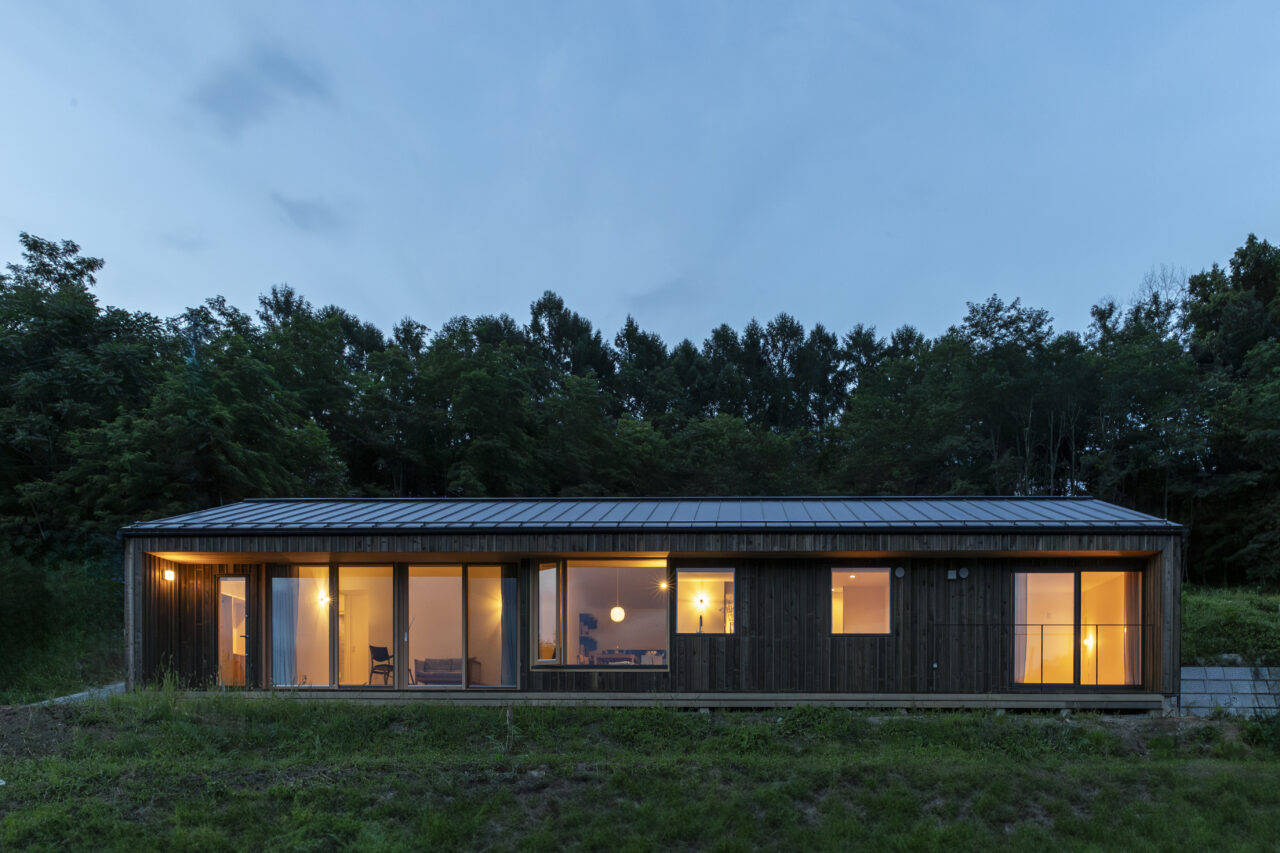 夜に浮かび上がる水平窓のある住まい